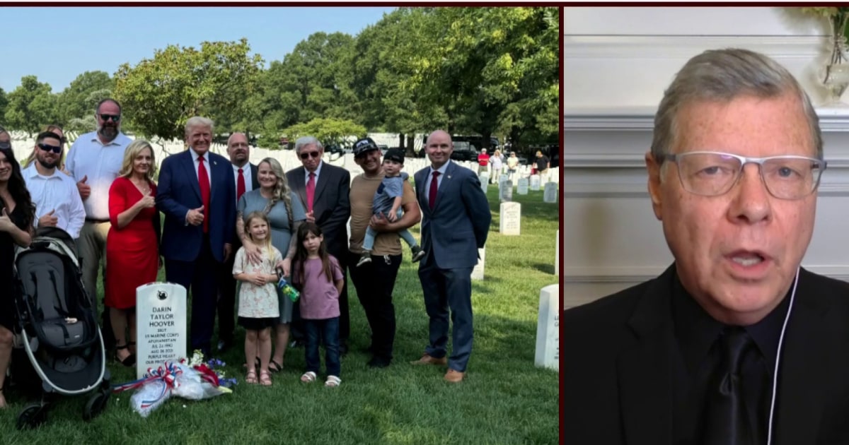 Who poses with a thumbs up in front of the grave of a fallen soldier?